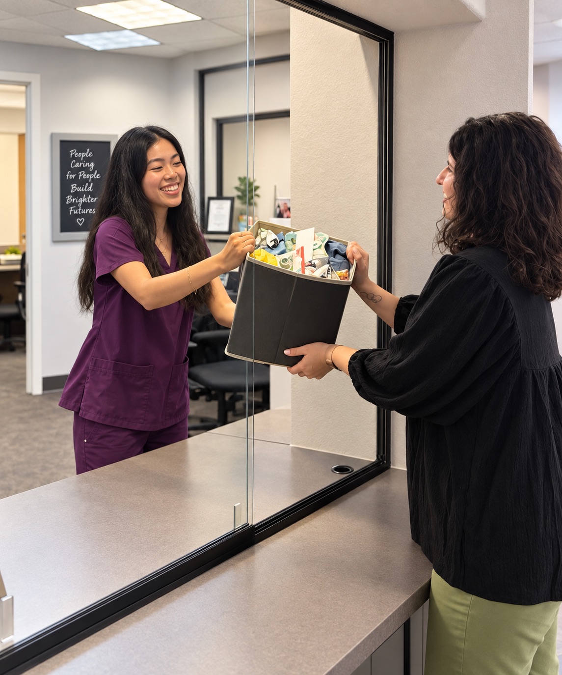 A PH4U staff member handing a client a basket of resources at the front desk